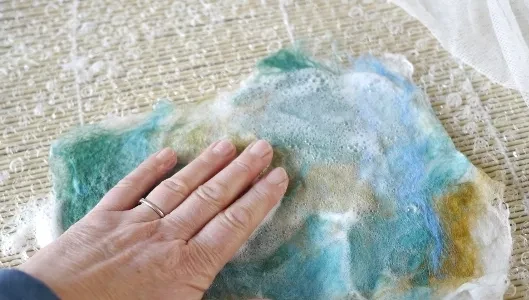 Hand working colourful wool fibres during felt making