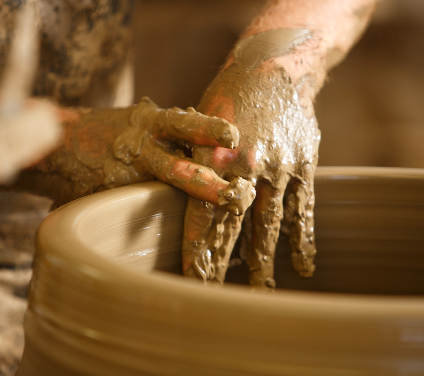 Hands shaping clay on a pottery wheel